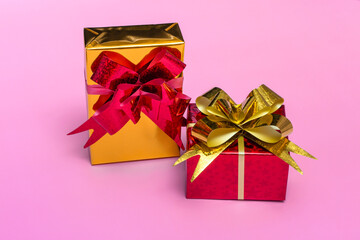 Beautiful golden gift boxes with a red bow on a colored background top view