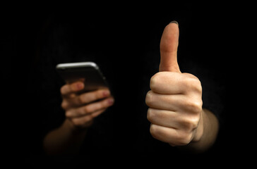 Application customer review concept. Mobile phone and thumb up excellent gesture on a black background photo