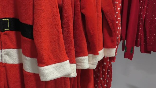 Red color Christmas Santa Claus robes or costumes hanging on rack in the shop.