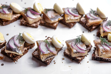 Snacks of rye bread with herring and onions are on a plate. Selective focus.