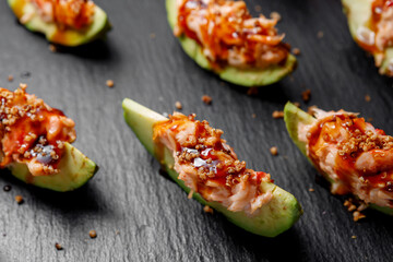 Sliced avocado seasoned with sauce lies on a dark background. Selective focus.