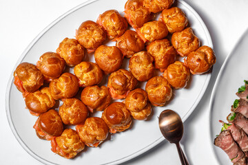 Profiteroles stuffed with fish, decorated with tomatoes. Flat layout.