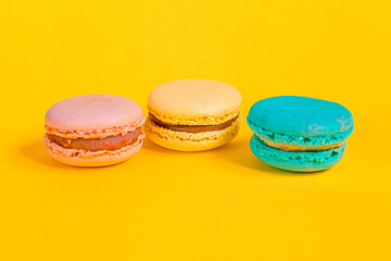 Sweet almond colorful unicorn pink blue yellow green macaron or macaroon dessert cake isolated on trendy yellow modern fashion background. French sweet cookie. Minimal food bakery concept. Copy space