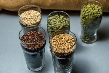 Malt for light and dark beer, hops in granules in glass glasses.