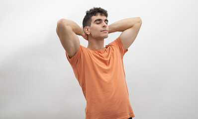 
a boy with his hands behind his head thinking on a white background.
concept of rest, no stress.
