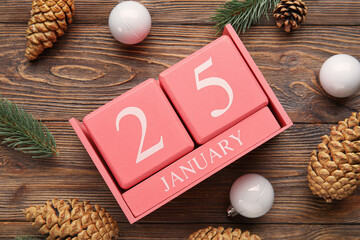 Calendar with date of January 25, pine cones, fir branches and Christmas balls on wooden background, closeup