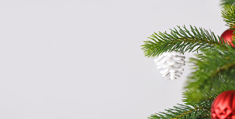 Christmas banner with white fir cone ornament on tree in front of gray background with copy space