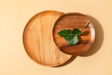 Wooden plates and ivy leaf on color background