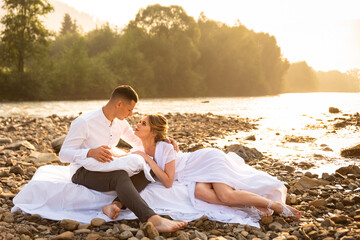 Loving couple in the summer in bed with white linen. A couple in the outdoors loves each other