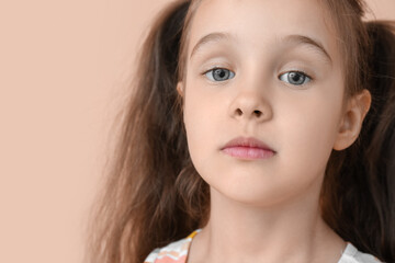 Portrait of cute little girl with ponytails on beige background, closeup