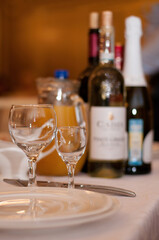 a wine glass and a shot glass are on the table next to bottles of wine, with a blurred background