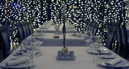 Photo for congratulations on Christmas and New City - 2022. Festive table: candle, glasses, plates, dishes, wine, etc.