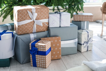 Gift boxes under Christmas tree in room, closeup