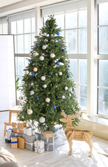 Beautiful decorated Christmas tree with gift boxes in light living room