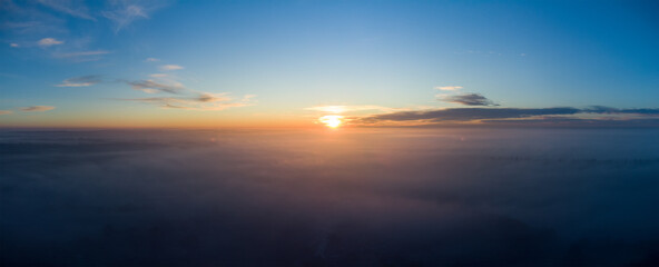 Naklejka na ściany i meble Sunrise over thick autumn fog. Panorama over the clouds in the morning.