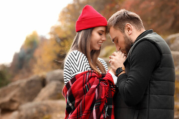 Young man kissing his girlfriend hands in beautiful autumn park