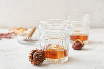Glasses of cold chestnut whiskey on light background