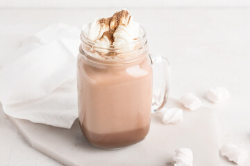 Mason jar of tasty coffee with cinnamon on white background