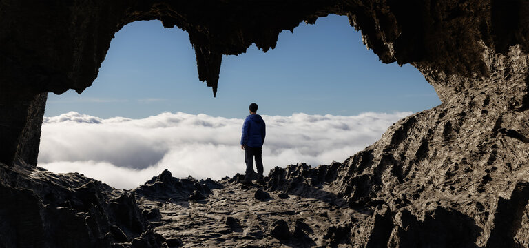 Dramatic Adventurous Scene with Man standing inside an Alien like Rocky Cave Landcspae. 3d Rendering Art. Aerial Cloudscape Image from British Columbia, Canada. Adventure Concept