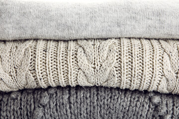 Stack of trendy grey sweaters as background