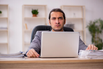 Young male employee unhappy with excessive work in the office