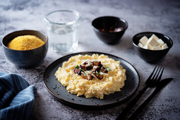 Corn porridge with fried bacon, parsley and Feta cheese in a bowl