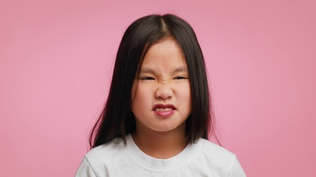 Disgusted Asian Girl Smelling Stinky Smell Frowning Over Pink Background
