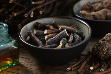 Black bowl of Common comfrey or symphytum officinale roots. Bottle of infusion or tincture. Dried comfrey officinalis roots, knitbone and Bistort, Snakeweed, Snake roots. Alternative herbal medicine.