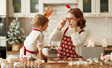 Joyful happy family mother and boy son having fun while baking christmas cookies in kitchen