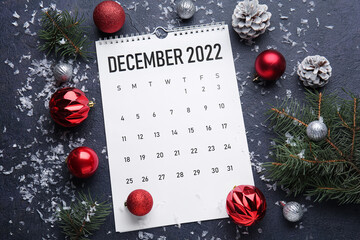 Paper calendar for December 2022 and Christmas decor on dark background