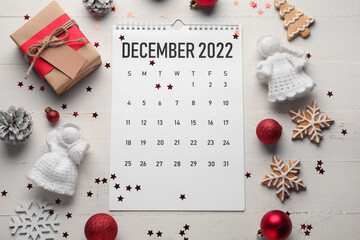Paper calendar for December 2022, Christmas decor and confetti on light wooden background - obrazy, fototapety, plakaty