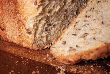 Close-up view of wheat bread with seeds and golden crust, cut on a wooden board. Homemade bread.
