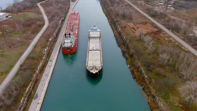 Two cargo ships maneuver inside the Beauharnois Canal in the St Lawrence Seaway, near Montreal, Quebec. High quality 4K aerial view.