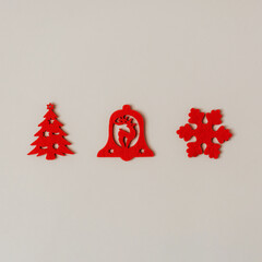 Red felt christmas tree ornaments depicting reindeer, snowflake and pine tree with shooting stars laid out on white background. Winter holidays minimal flat layout concept.