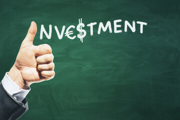 Close up of businessperson hand showing thumbs up on chalkboard background with investment sketch, dollar sign and mock up place. Invest, money and education concept.