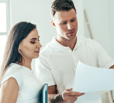 woman designer and a young man standing in an empty apartment.