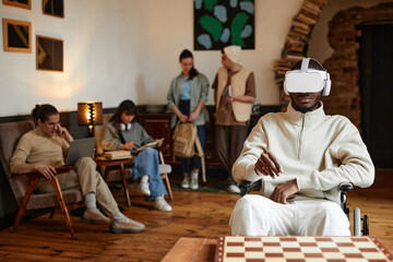 African man sitting in wheelchair in vr glasses to play virtual reality game during his leisrure time in the campus