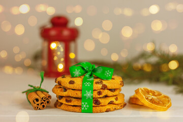 close up cookies with raisins tied with green Christmas ribbon, lemon slices and cinnamon against a red lantern background. festive pastries and desserts
