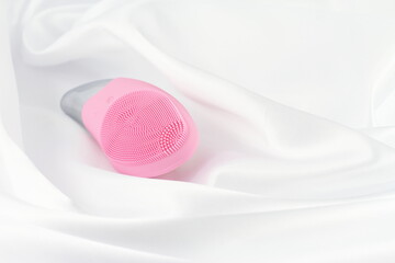 Pink facial sonic brush on white silk 