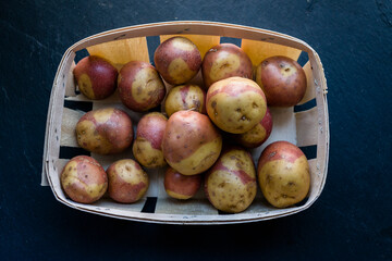 Canary islands potatoes, pink variety in a basket over dark backround (Canarian pink potatoes)