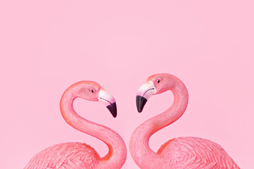 Trendy summer composition with two pink flamingos forming a heart on pink background. Valentine's day concept
