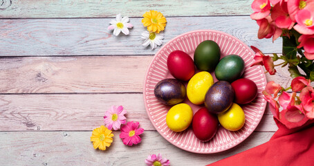 Fototapeta na wymiar Colorful panted Easter eggs on pink plate and pastel color background with flowers. Easter spring holidays