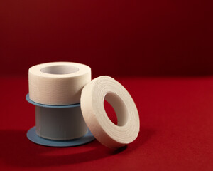 adhesive plasters of different types and colors on a burgundy background in a low key