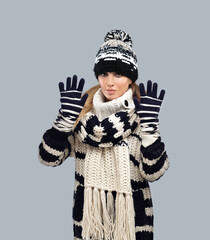 Winter portrait of a beautiful young woman wearing sweater posing against blue background.