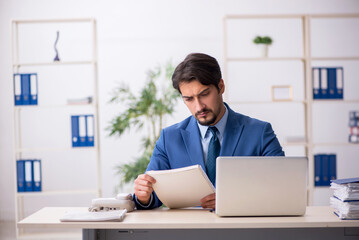 Young male employee and too much work in the office