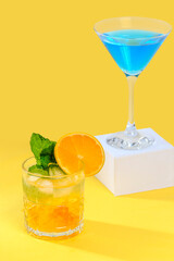 orange cocktail and blue cocktail on an orange colored
