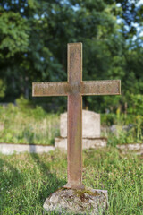 Old abandoned rusty cross in the cemetery.
