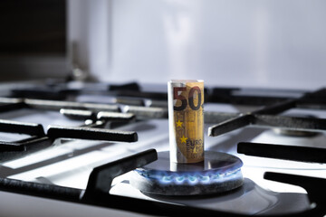 Concept of gas crisis. 50 euro bank note is burning on a kitchen stove. Cash money. High prices of...