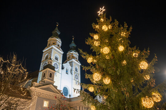 Cathedral of Santa Maria Assunta in Bressanone, Brixen. The towers of the square illuminated in the night with Christmas and the Christmas tree.