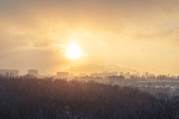 Aerial drone top view of scenic warm sunrise morning sun shine through snowstorm vortex blizzard against city building cityscape panoramic urban background. Winter snowfall storm and sunny weather